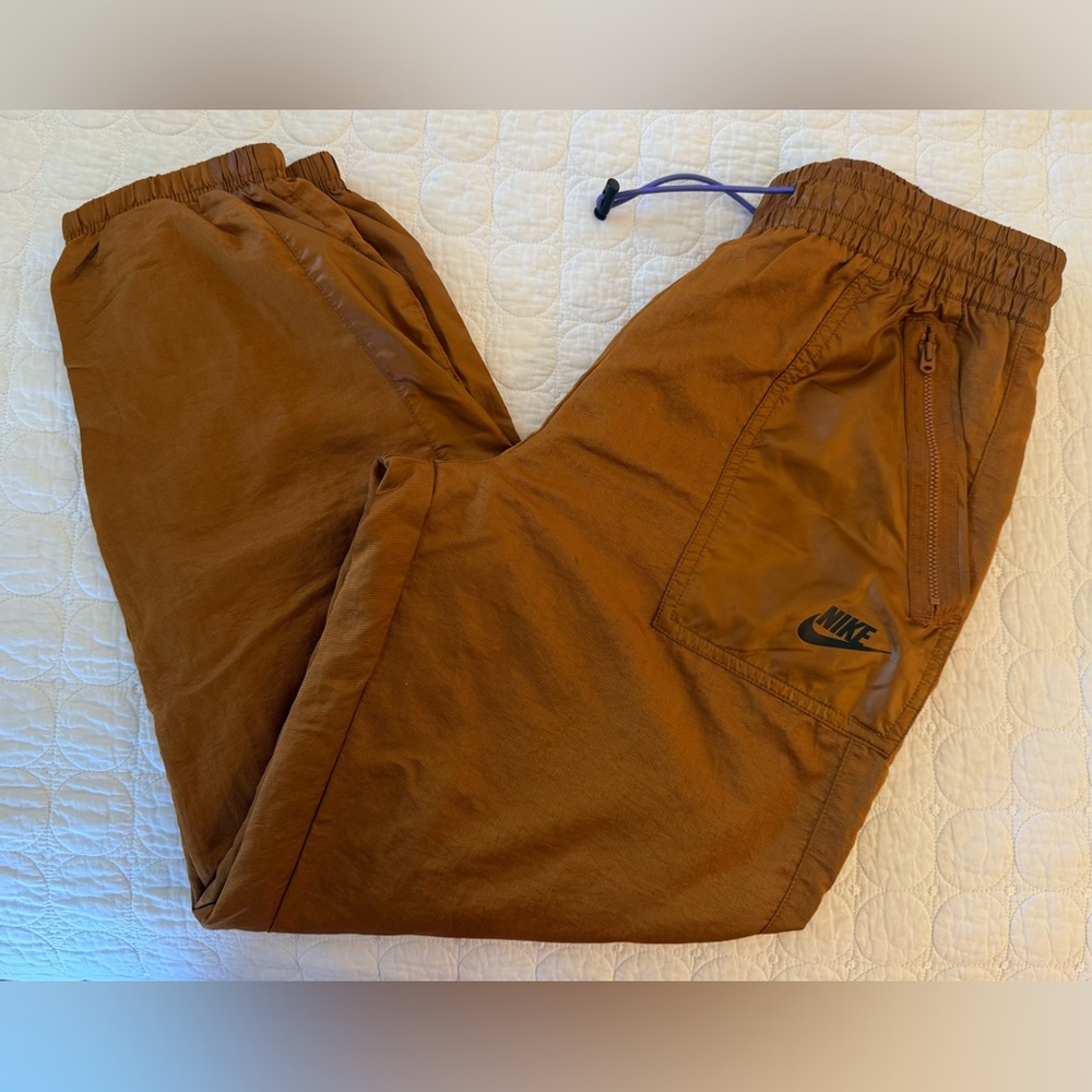 Brand new never worn Nike Track Pants with elastic waistband, burnt orange color